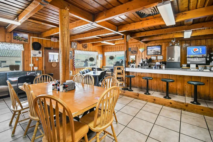 Dining room with a wood ceiling with exposed beams, wooden walls, and light tile patterned floors