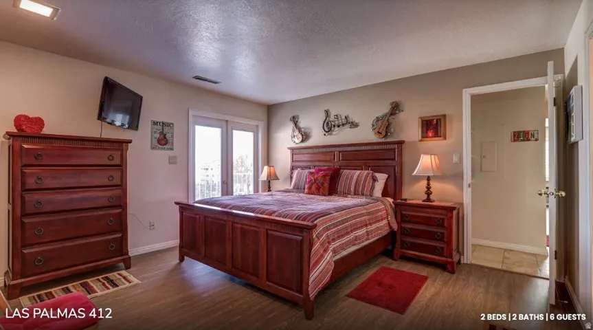 Bedroom with a textured ceiling, dark wood-style floors, and access to outside