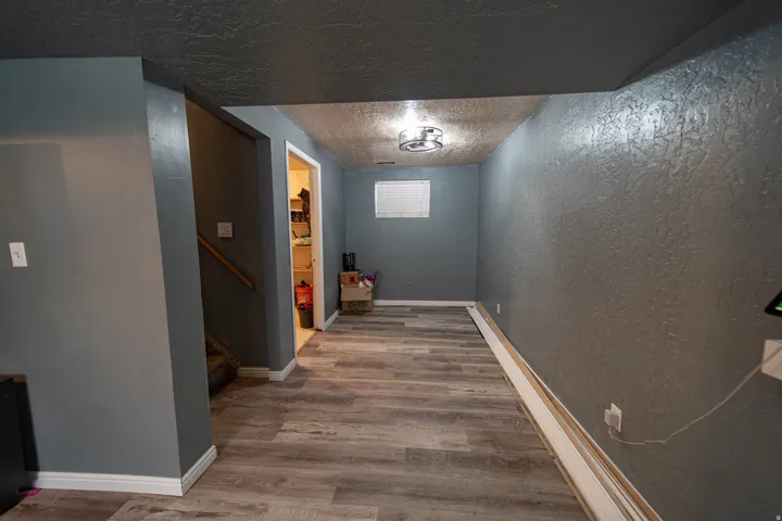 Hallway with a textured wall, wood finished floors, a textured ceiling, and stairs