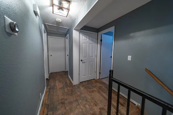 Hallway with a textured ceiling, dark wood finished floors, and a textured wall