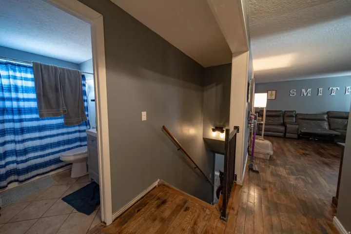 Stairs featuring a textured ceiling and hardwood / wood-style floors