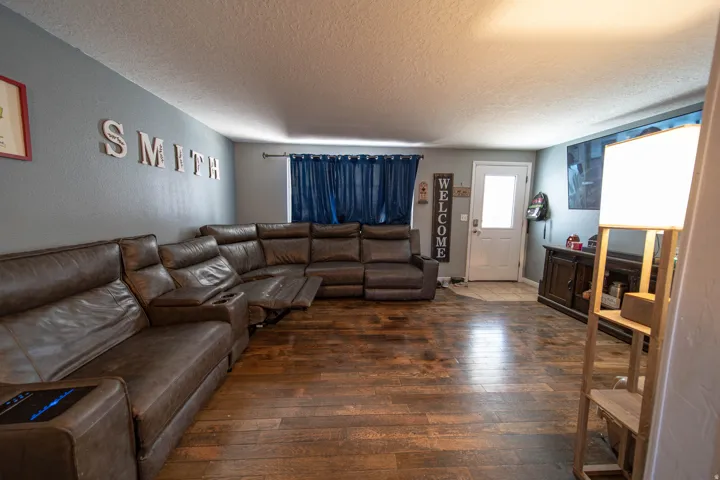 Living area with dark wood-style floors, a textured ceiling, and a textured wall