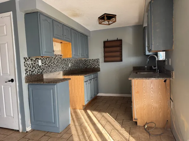 Kitchen with dark stone countertops, decorative backsplash, a textured ceiling, and gray cabinets