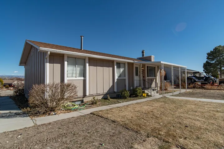 Single story home with a chimney, board and batten siding, and a front yard