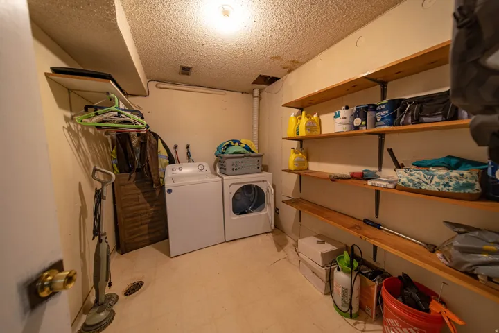 Washroom featuring light flooring, a textured ceiling, and washing machine and clothes dryer