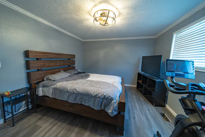 Bedroom featuring a textured ceiling, crown molding, and wood finished floors