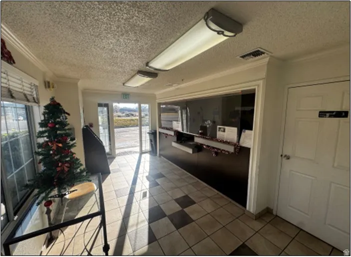 Interior space with a textured ceiling, ornamental molding, and light tile patterned floors