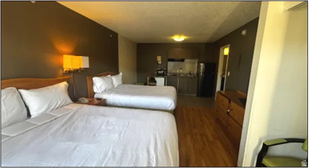 Bedroom featuring freestanding refrigerator, wood finished floors, and a textured ceiling