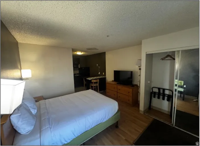 Bedroom with wood finished floors, a closet, and a textured ceiling