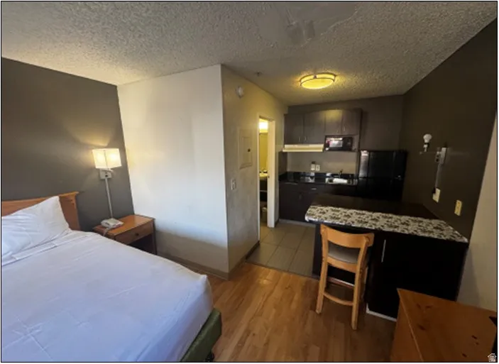 Bedroom featuring freestanding refrigerator, light wood-type flooring, and a textured ceiling