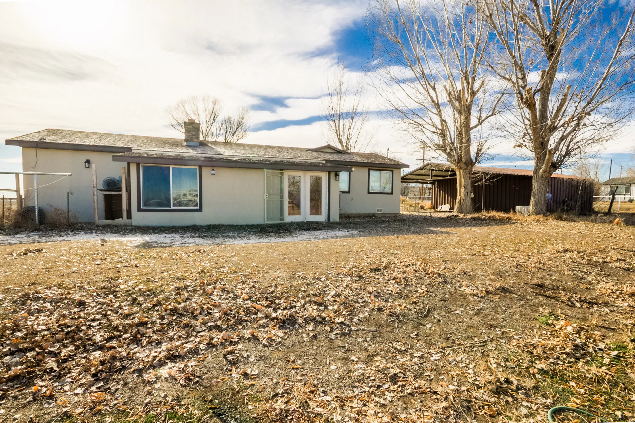 Back of property with french doors, a chimney, and stucco siding