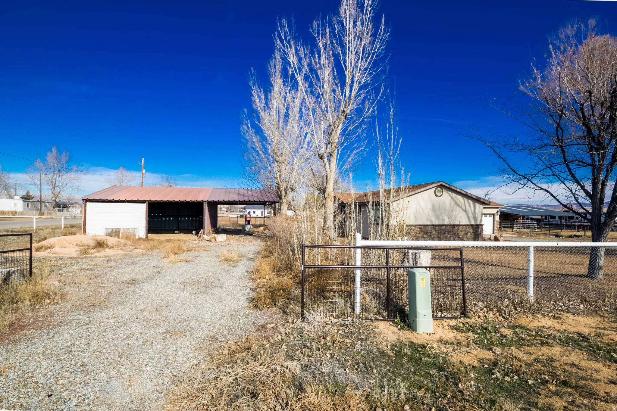 View of dirt / gravel road with a gated entry and an outbuilding