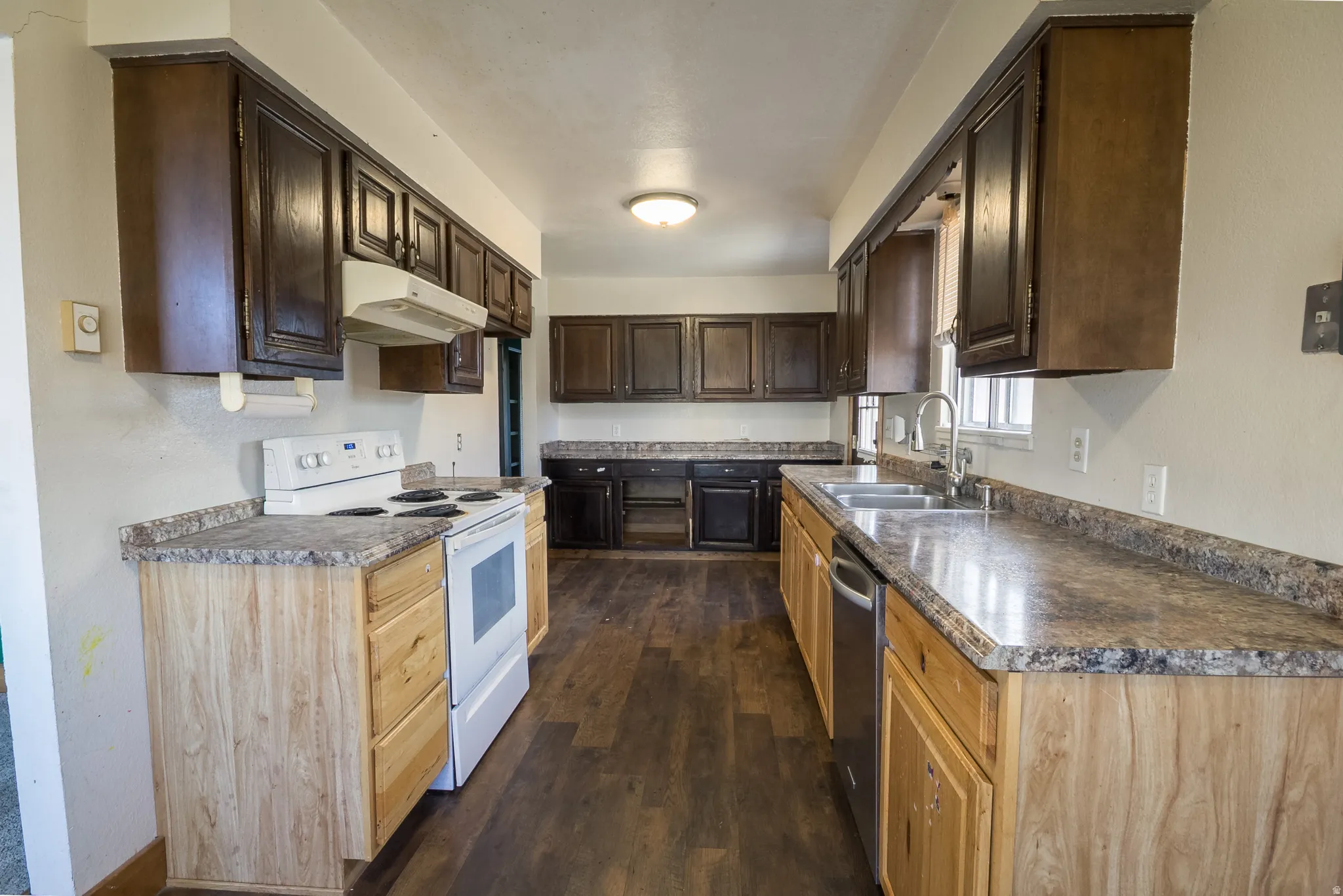 Kitchen featuring white electric stove, dark brown cabinets, dark wood-style flooring, and dark countertops