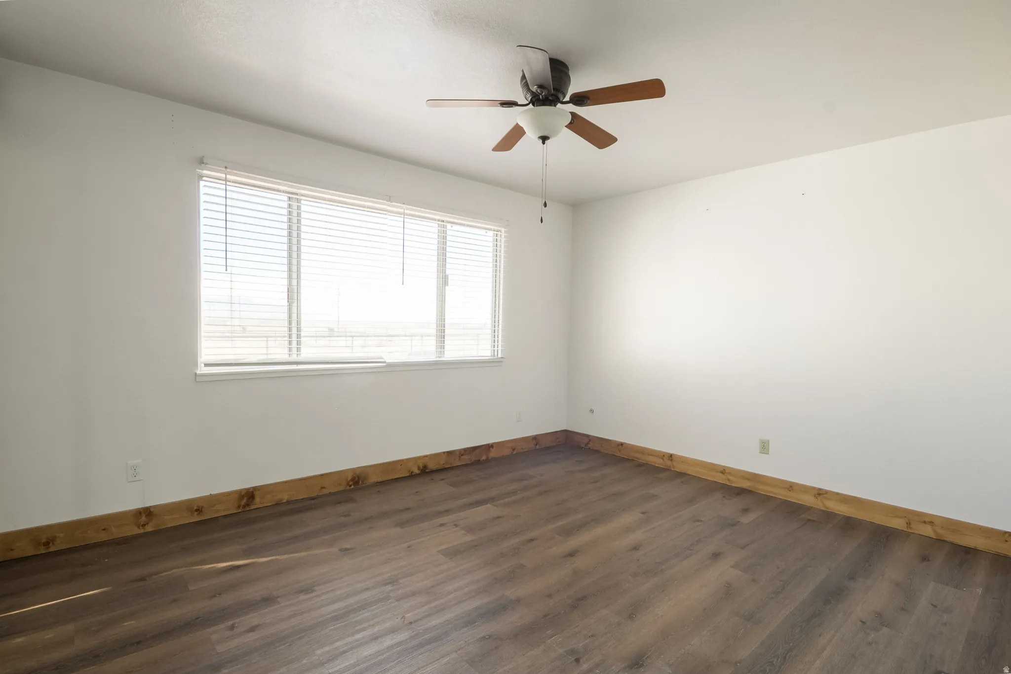 Spare room with dark wood-type flooring and ceiling fan