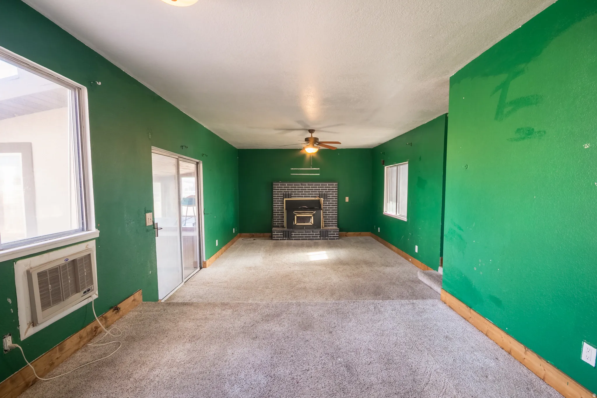 Unfurnished living room with carpet floors, ceiling fan, plenty of natural light, and a fireplace