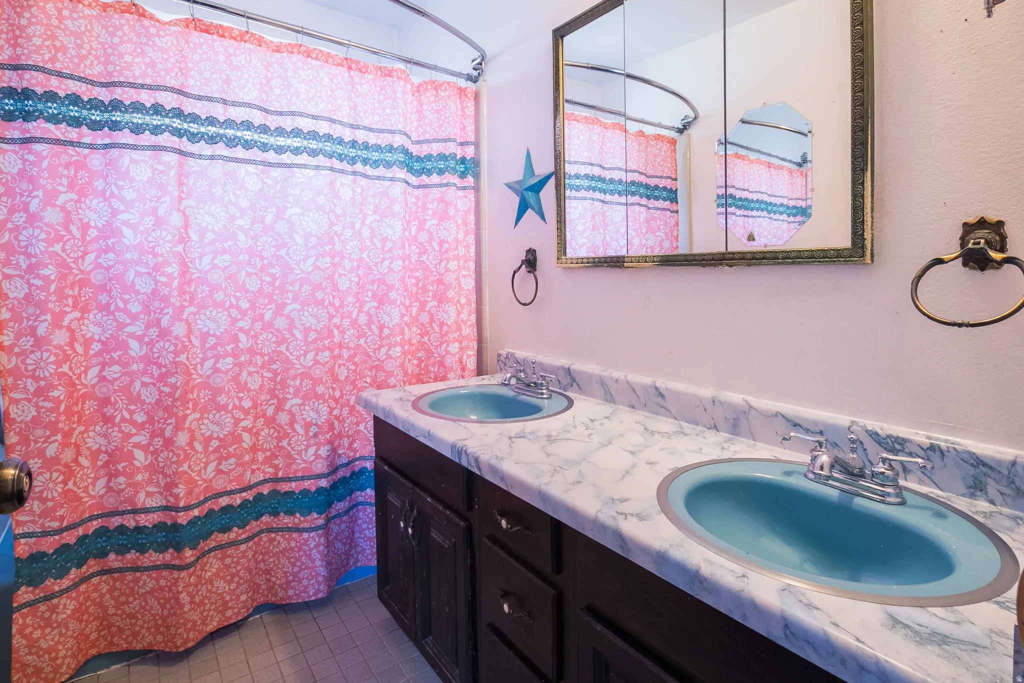 Bathroom featuring double vanity, curtained shower, and dark tile patterned floors