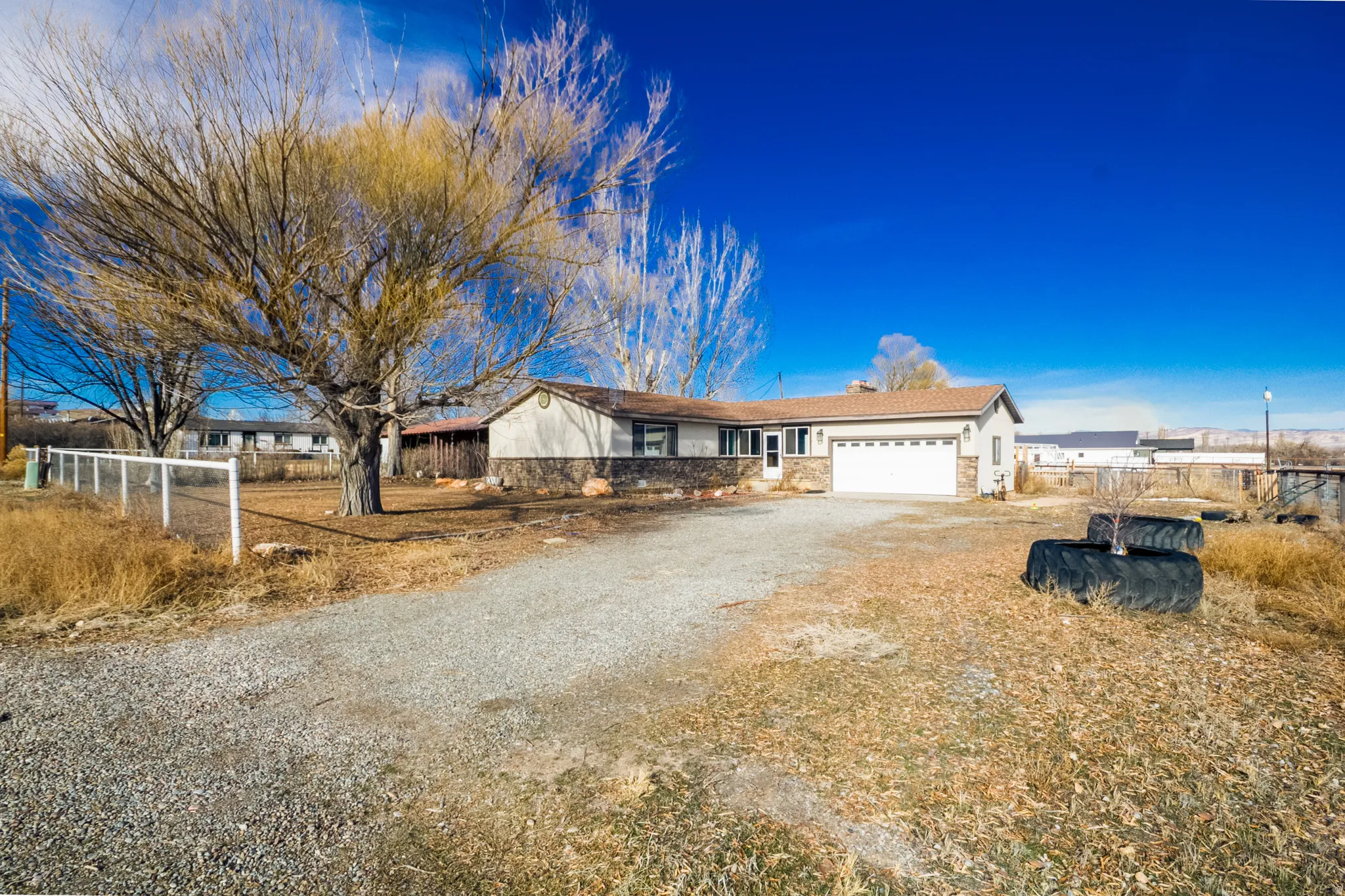 Ranch-style home with dirt driveway and an attached garage