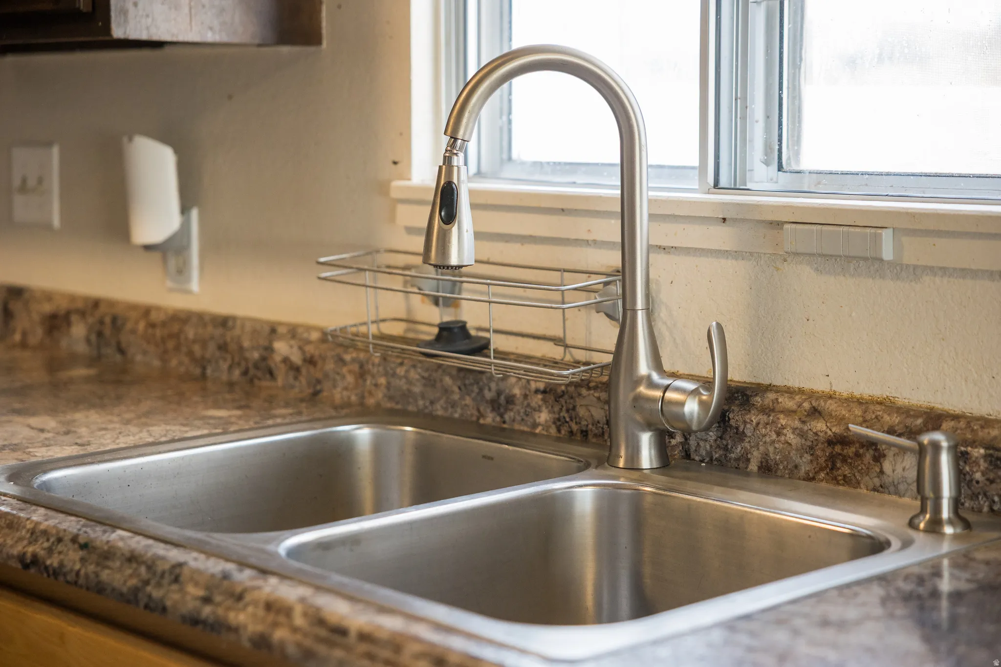 Kitchen view of a sink and dark countertops