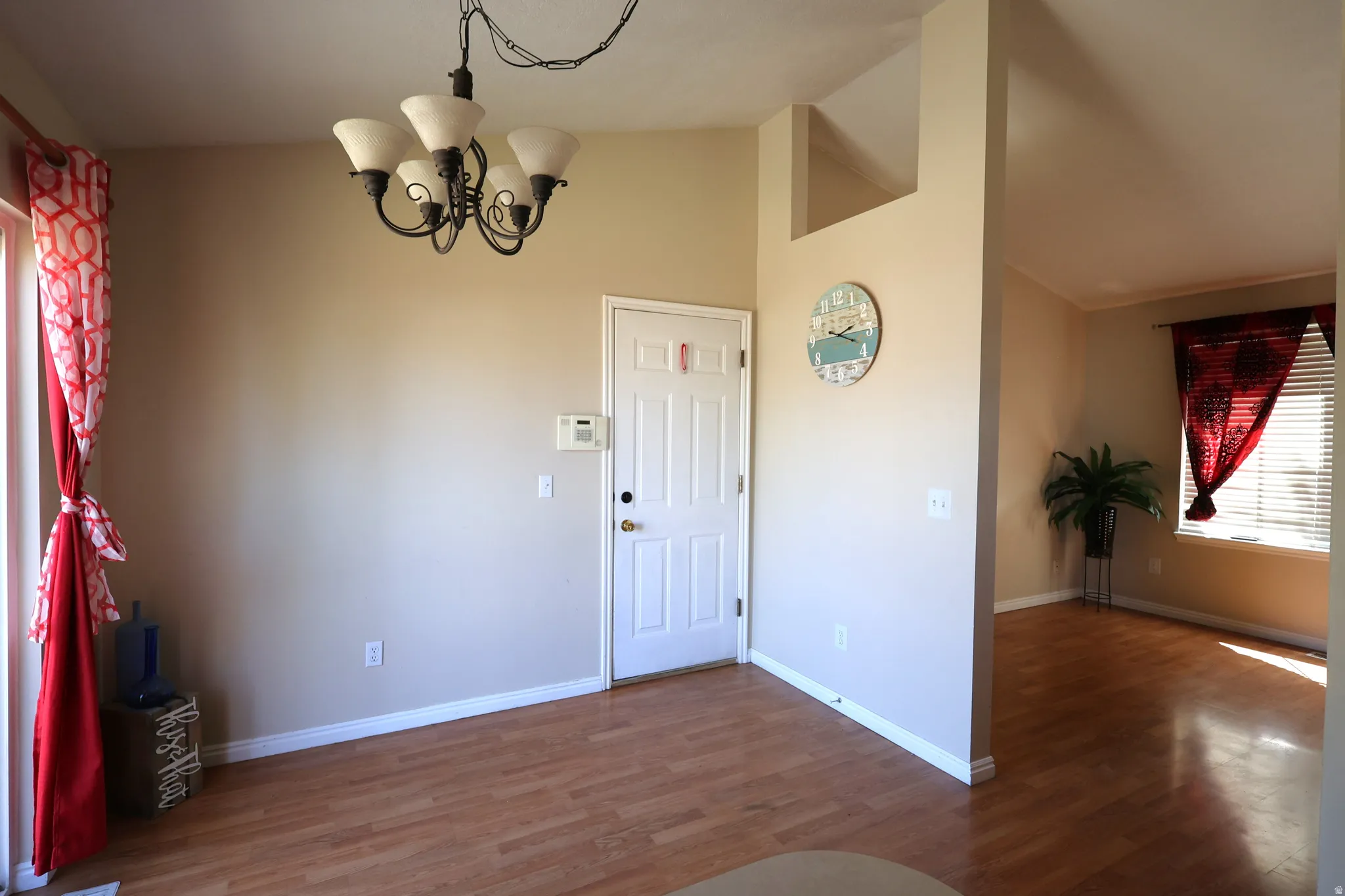 Foyer entrance featuring wood finished floors, a chandelier, and high vaulted ceiling