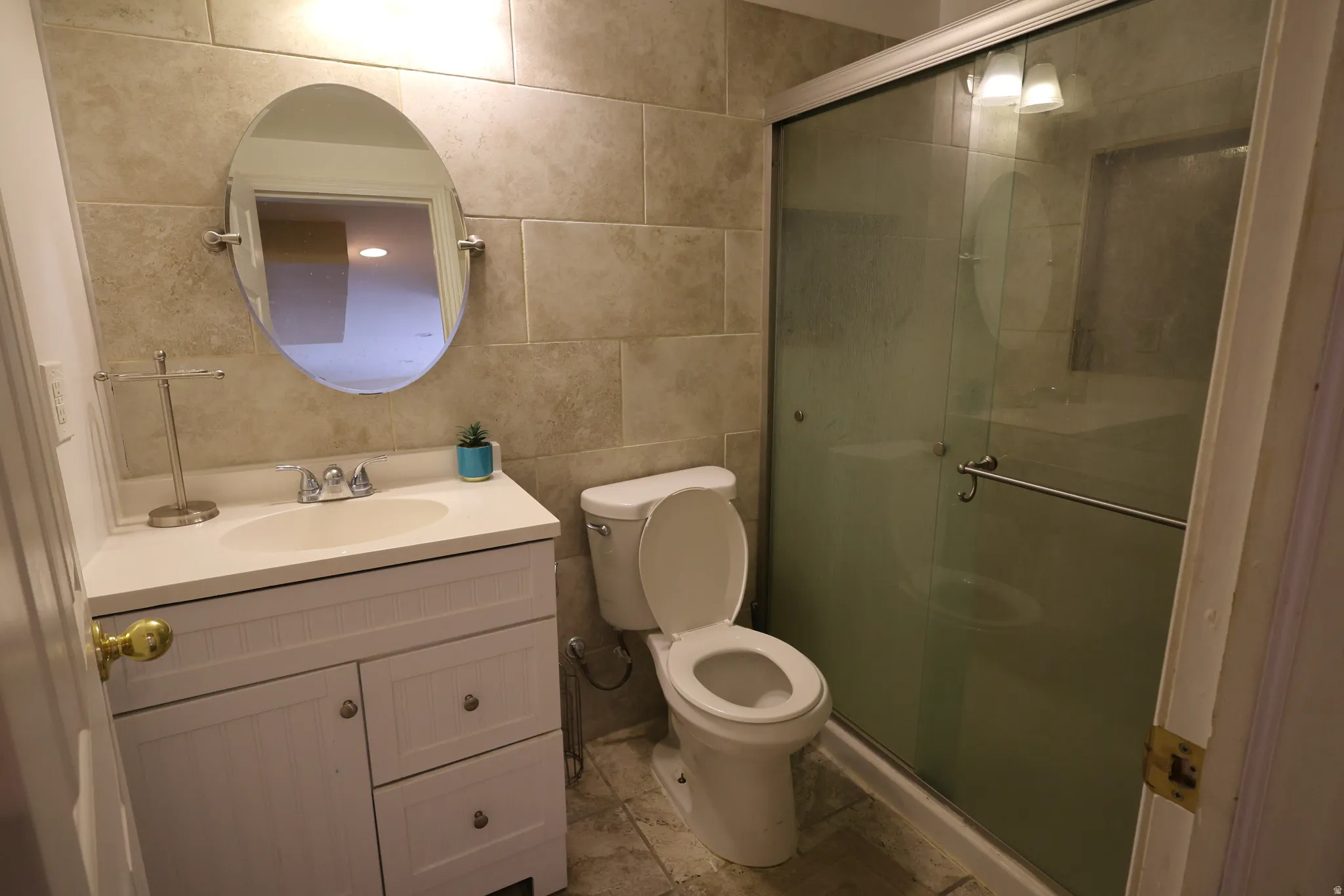 Full bath with tile walls, vanity, and a shower stall
