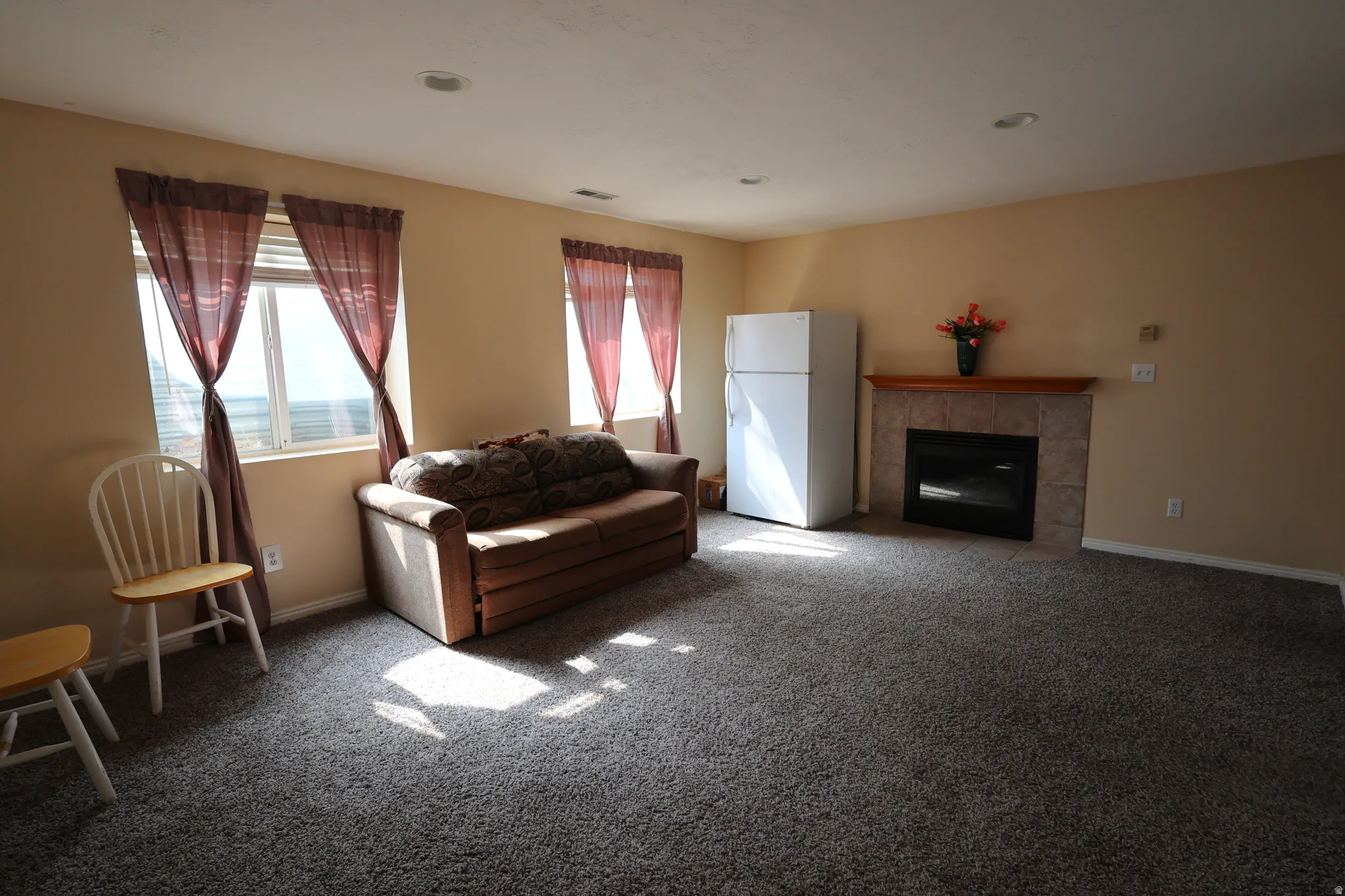 Carpeted living room featuring a tiled fireplace and recessed lighting
