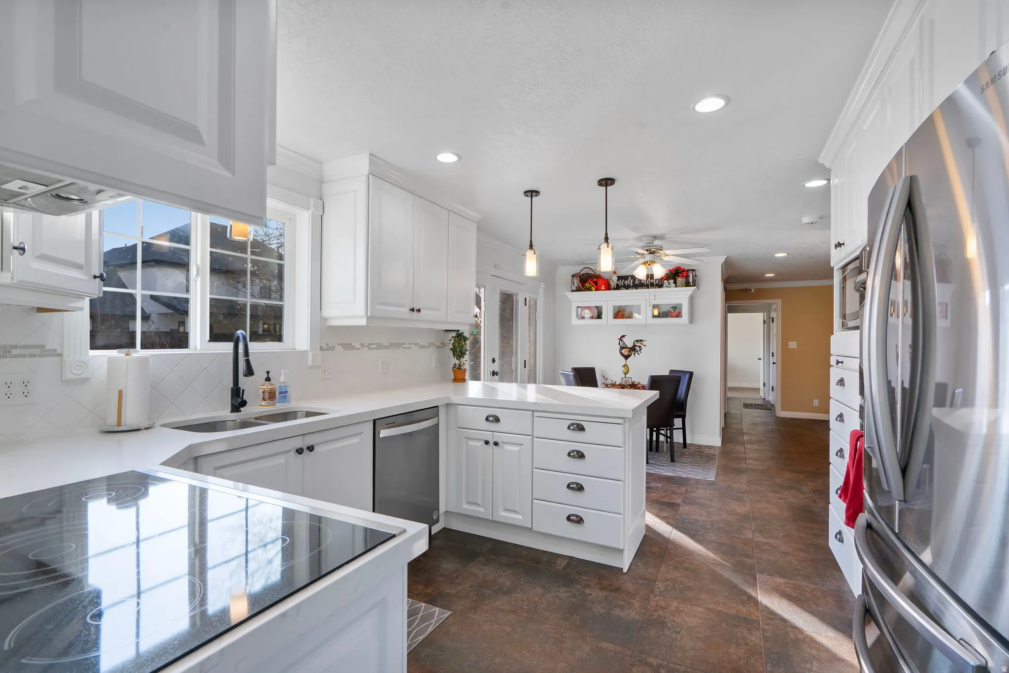 Kitchen with appliances with stainless steel finishes, white cabinetry, a peninsula, recessed lighting, and pendant lighting