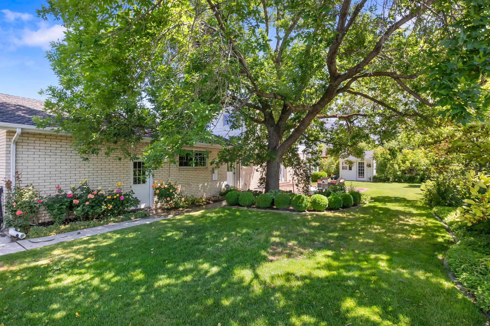 Spacious backyard featuring a manicured lawn, established shade trees, and a detached structure