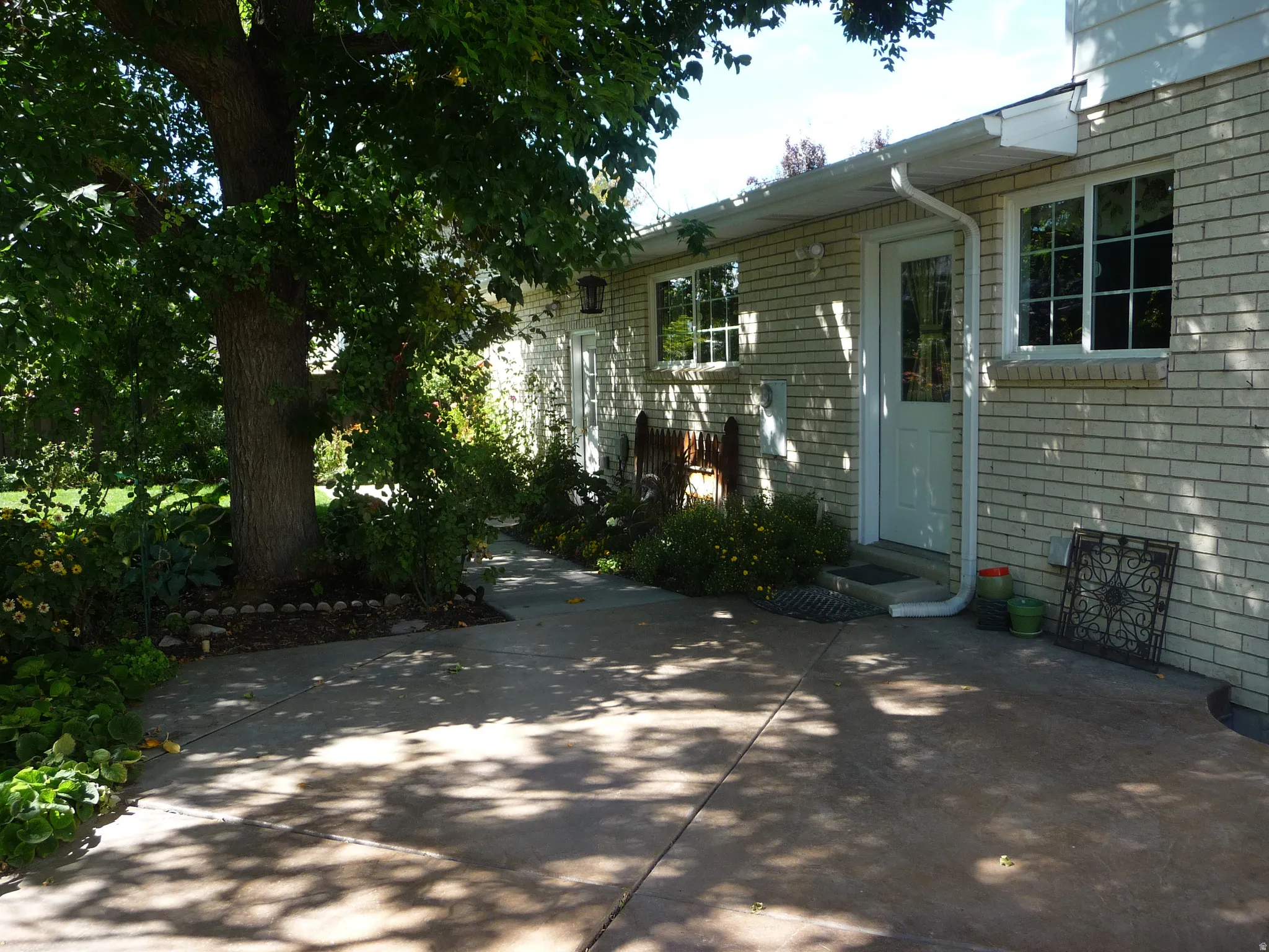 Side exterior featuring light brick facade, white trim, and multiple windows with grids