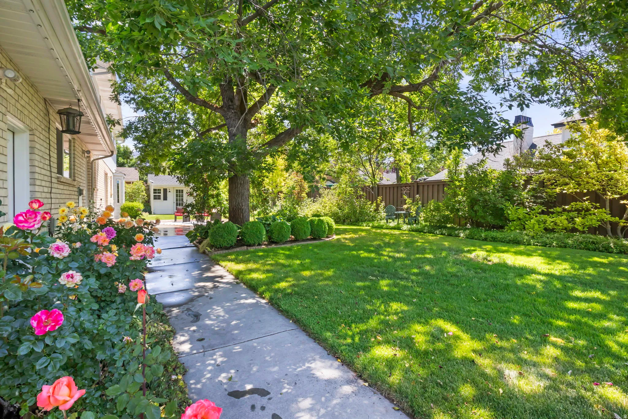 Expansive lawn with mature trees, established landscaping, and a concrete pathway leading to a detached structure