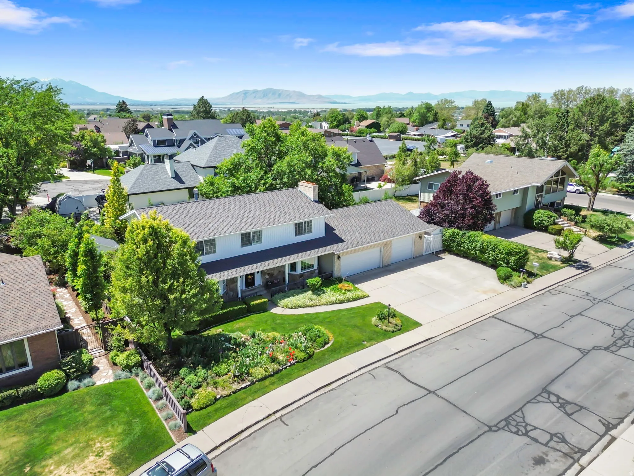 Two-story residence featuring a two-car garage, established landscaping, and a defined front garden bed