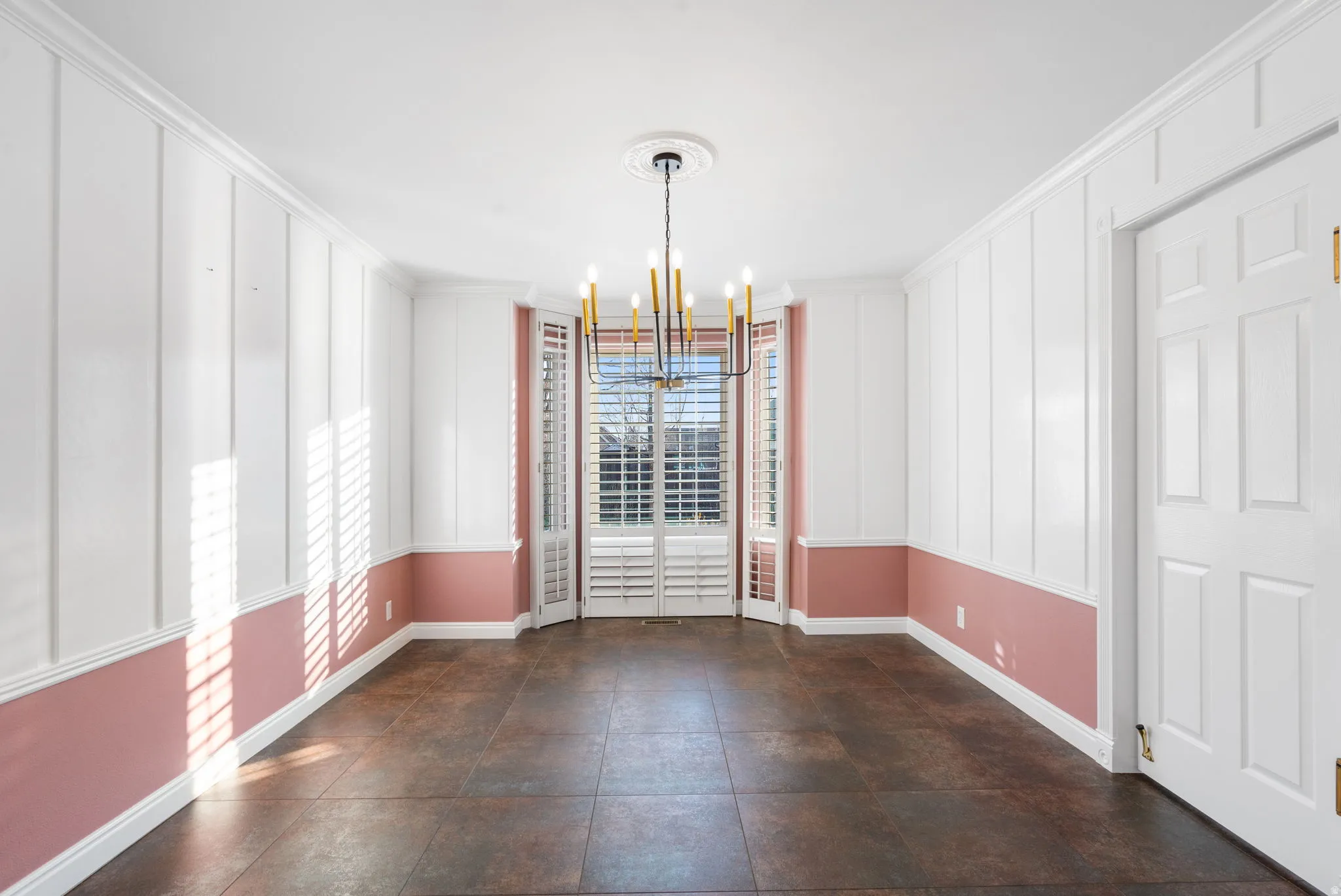 Unfurnished dining area featuring a chandelier, plantation shutter on bay window and ornamental molding