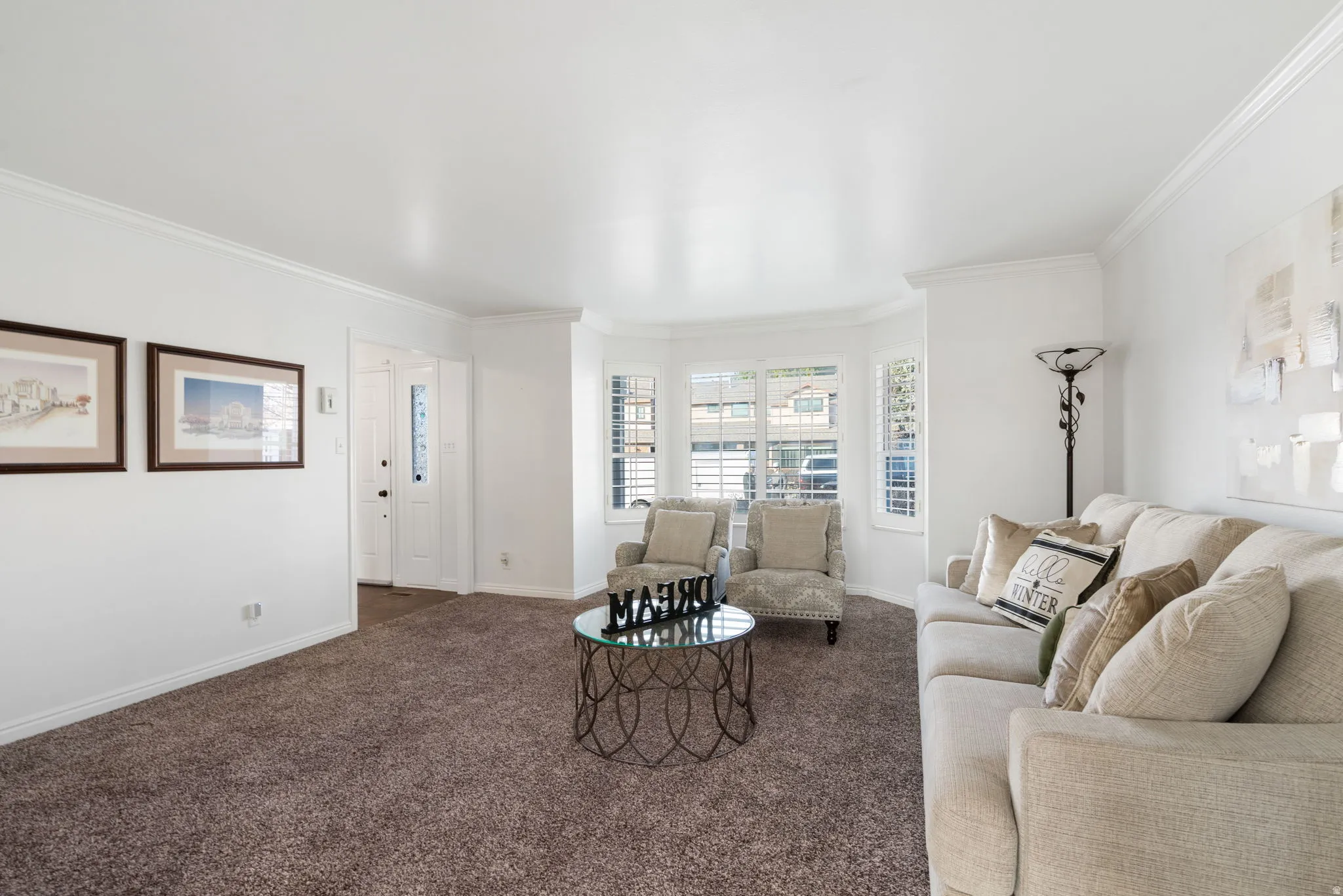 Living room with ornamental molding, plantation shutters and carpet floors