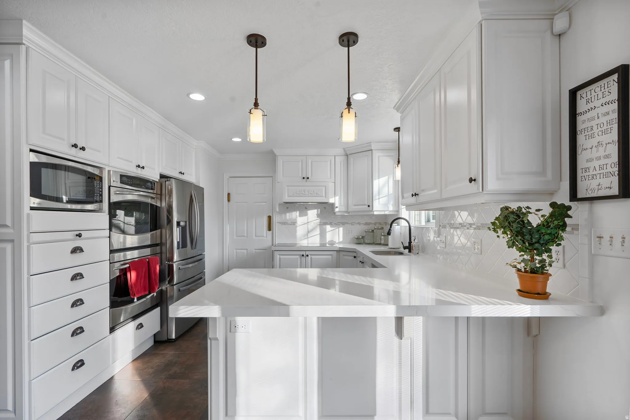 Kitchen with pendant lighting, white cabinetry, appliances with stainless steel finishes, a breakfast bar area, and recessed lighting