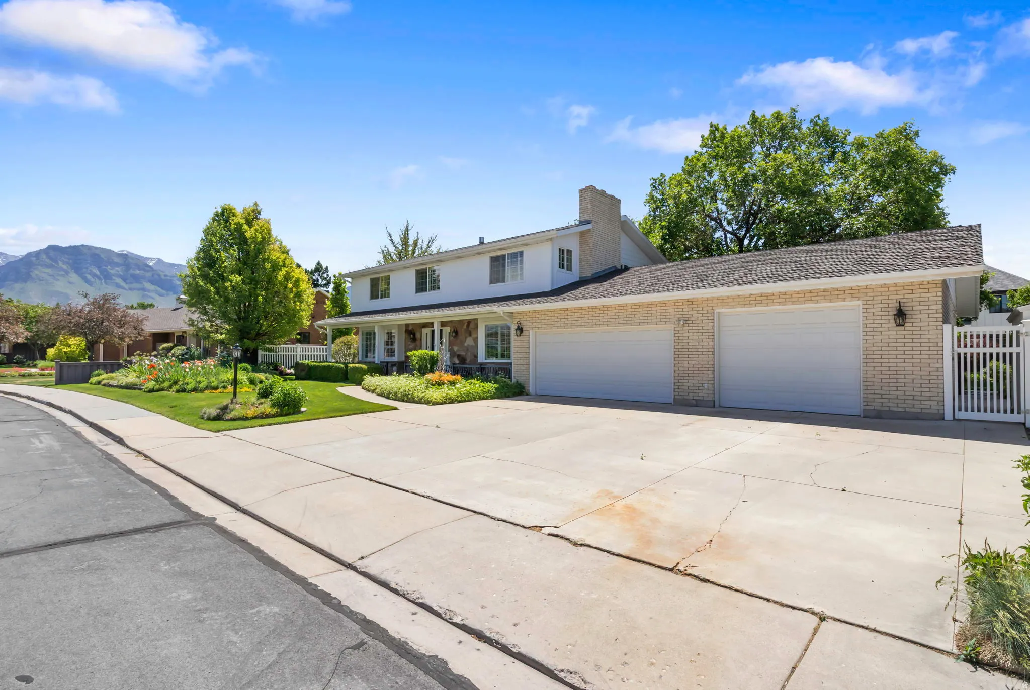 Traditional two-story residence featuring a dual-bay attached garage, a long paved driveway, and a covered front porch with stone accents