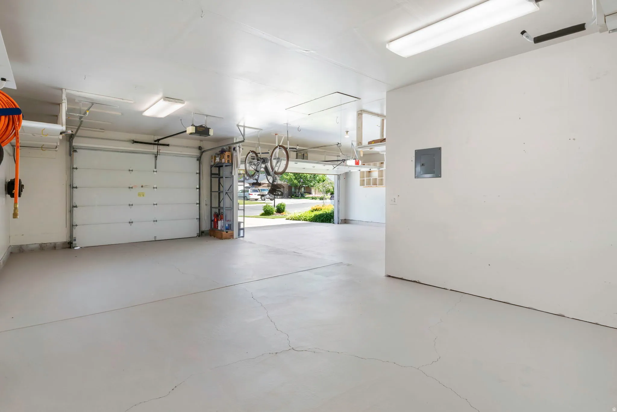 Spacious garage featuring light-toned epoxy flooring, white walls, and fluorescent overhead lighting