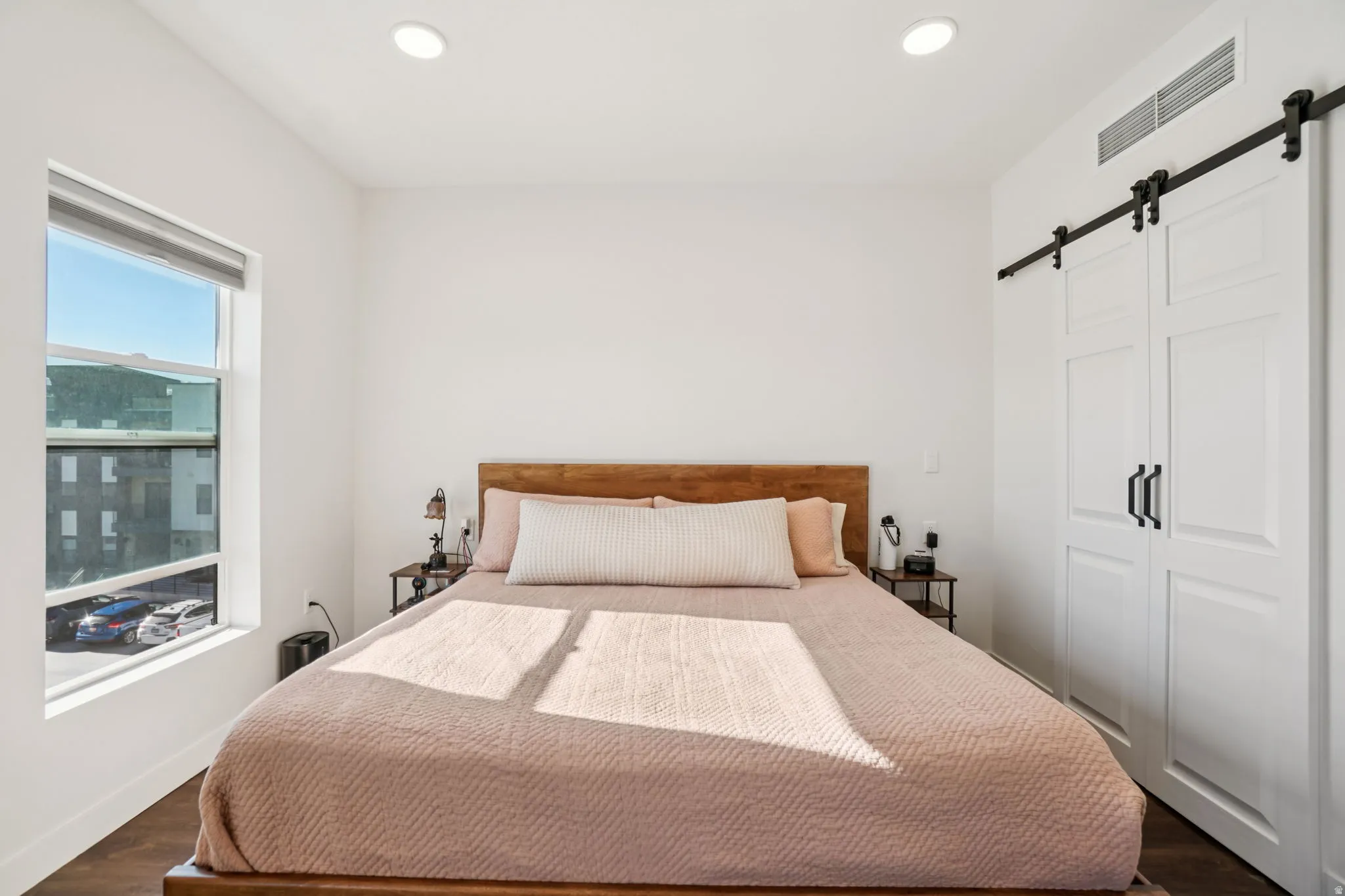 Bedroom with a barn door, a closet, dark wood-style flooring, and recessed lighting