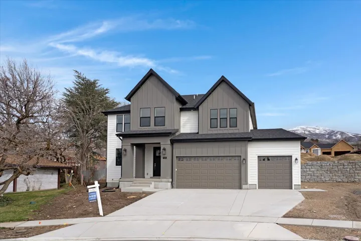 Modern inspired farmhouse with board and batten siding, driveway, a mountain view, and an attached garage