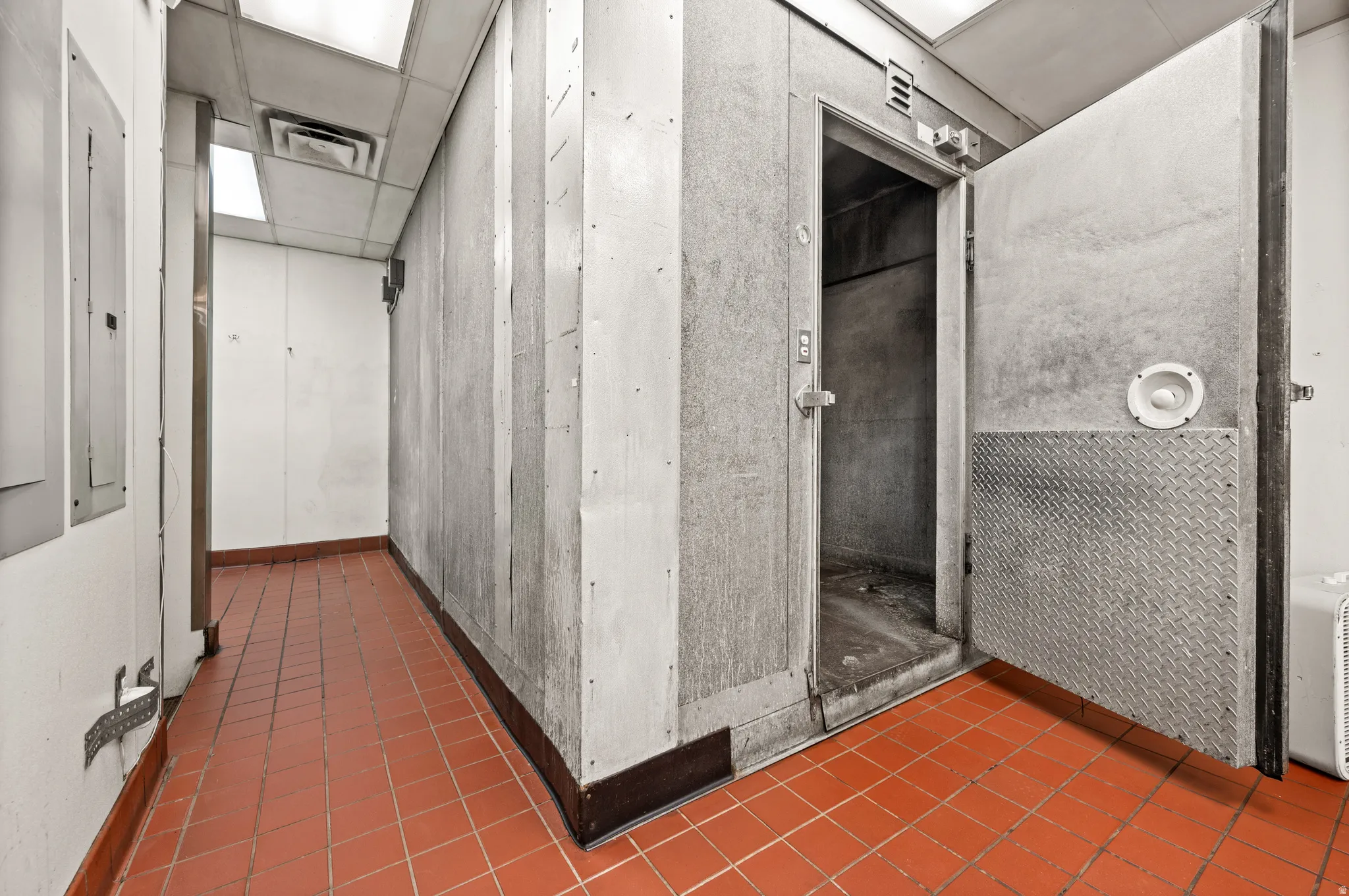 Corridor with dark tile patterned flooring, a paneled ceiling, and electric panel