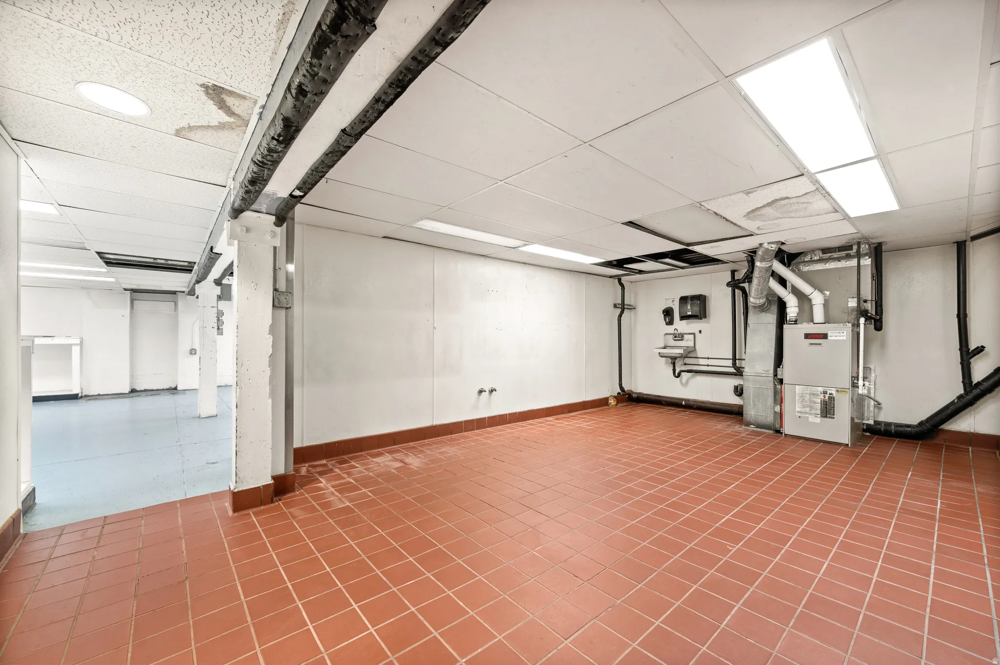 Finished basement featuring a paneled ceiling and heating unit