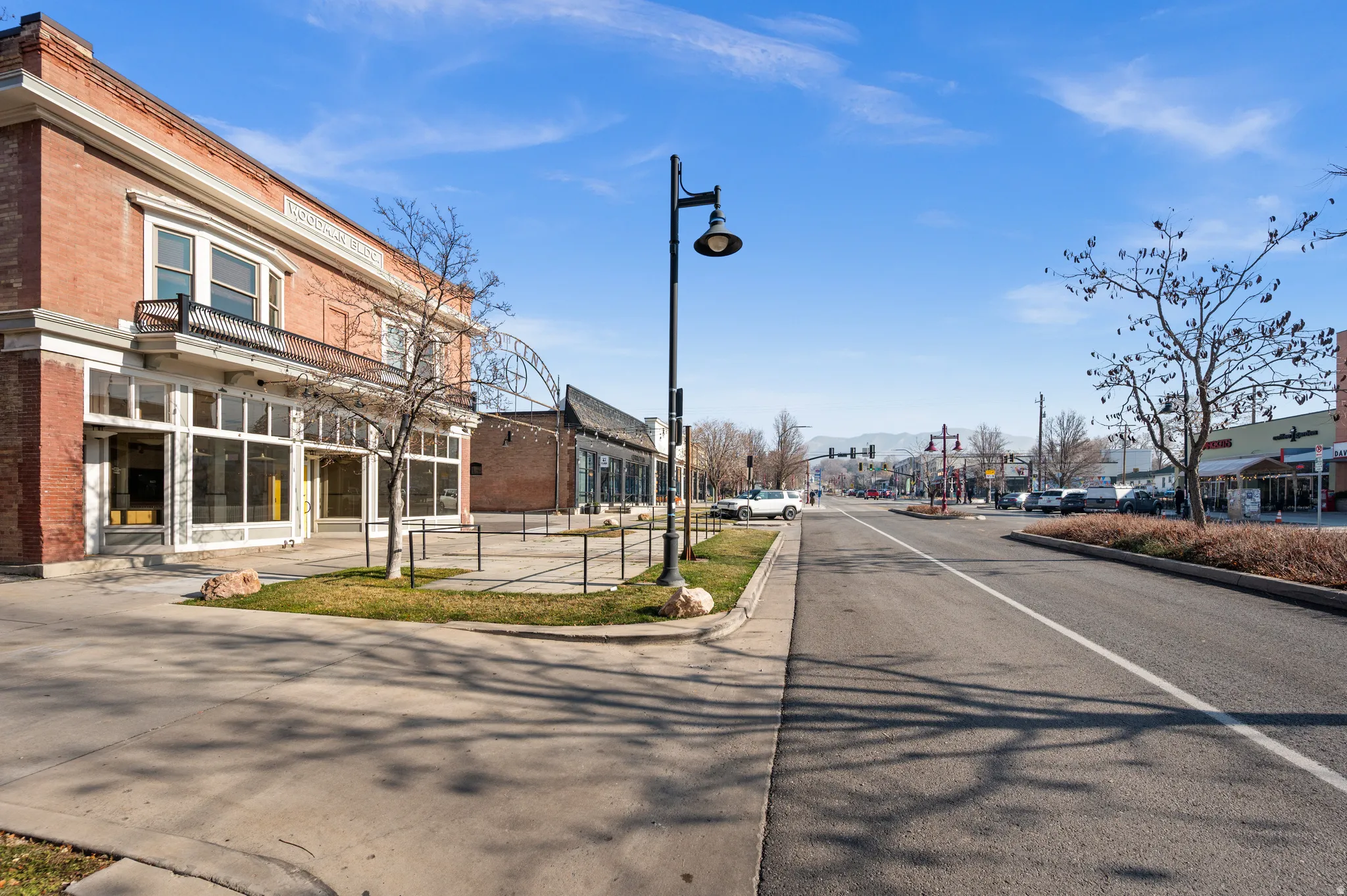 View of asphalt street with curbs, traffic lights, and street lights