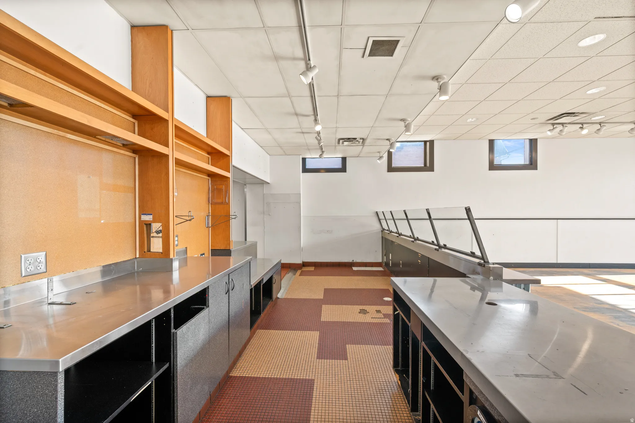 Kitchen with stainless steel countertops, dark cabinetry, and open shelves