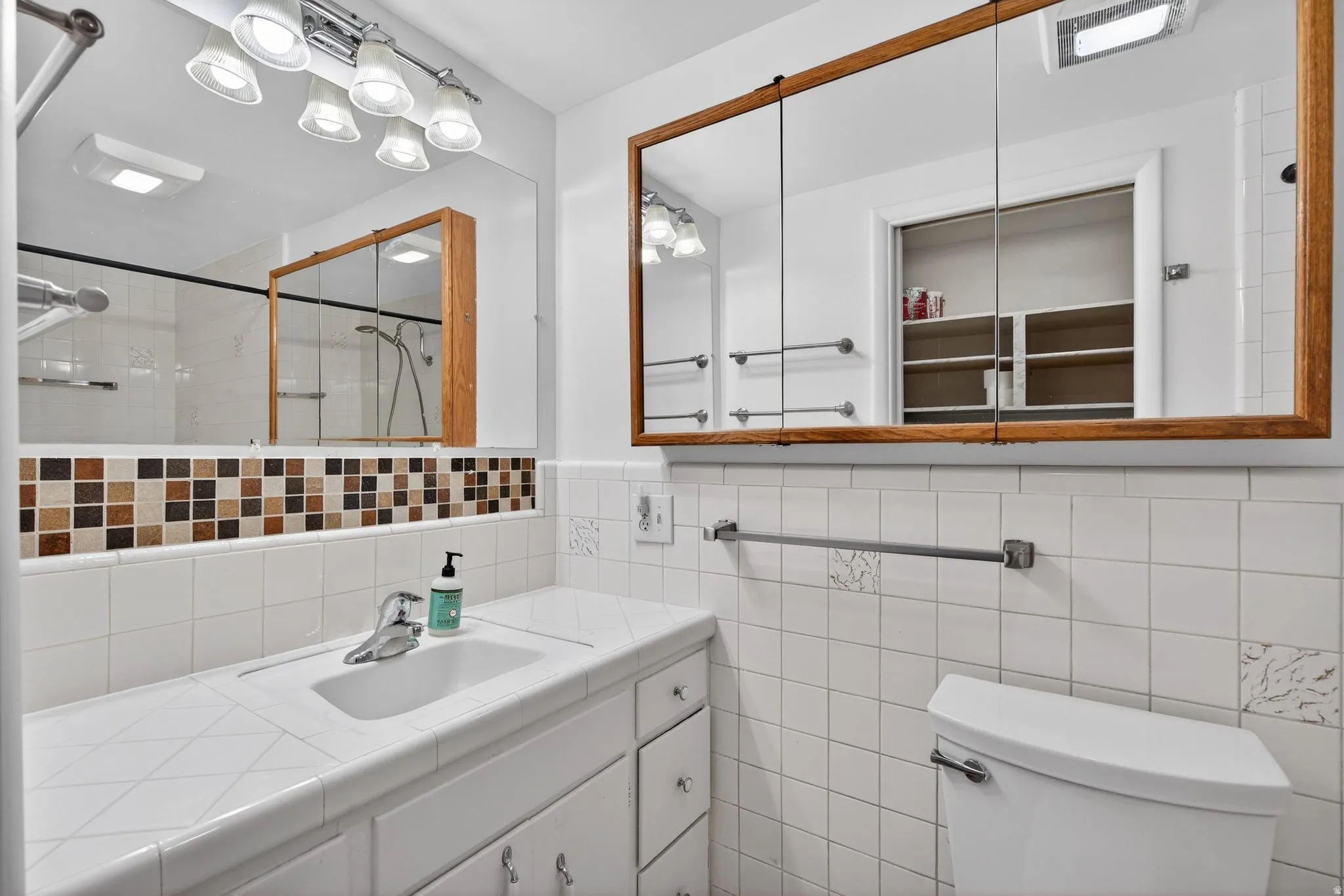 Bathroom featuring vanity, a tile shower, and tile walls