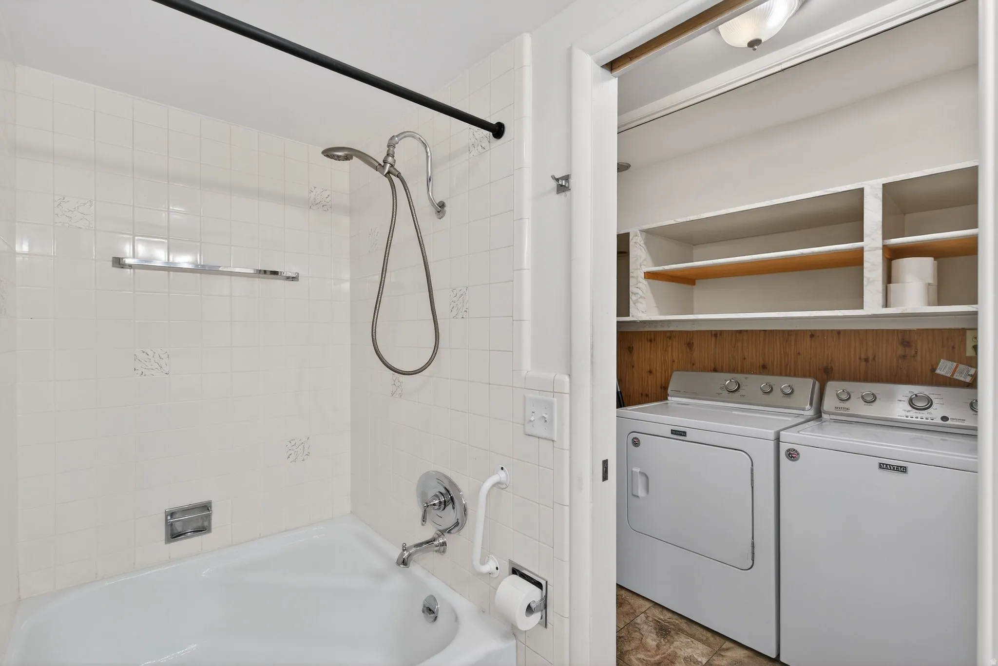 Bathroom featuring shower / washtub combination and view of independent washer and dryer