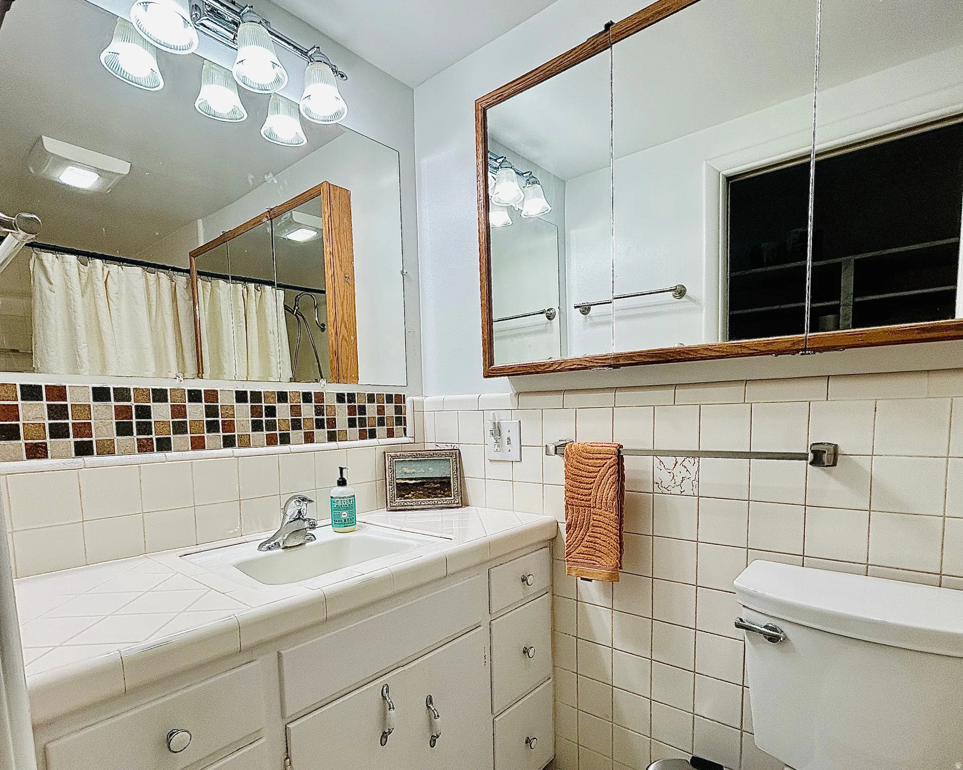 White tiled bathroom with a mosaic tile accent border