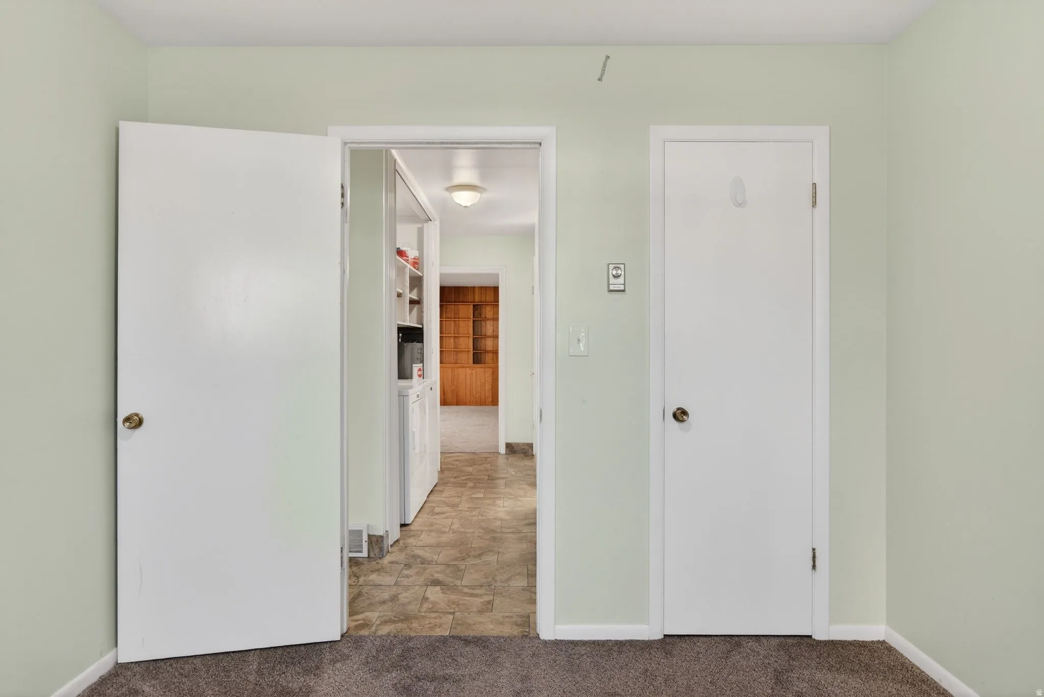 Secondary bedroom with closet and view of corridor with washing machine and clothes dryer