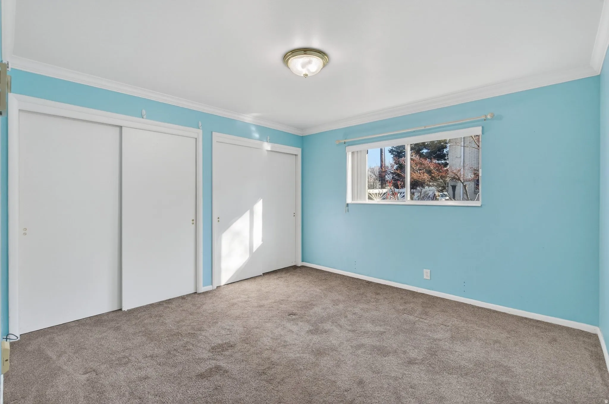 Unfurnished bedroom with two closets, crown molding, and carpet floors