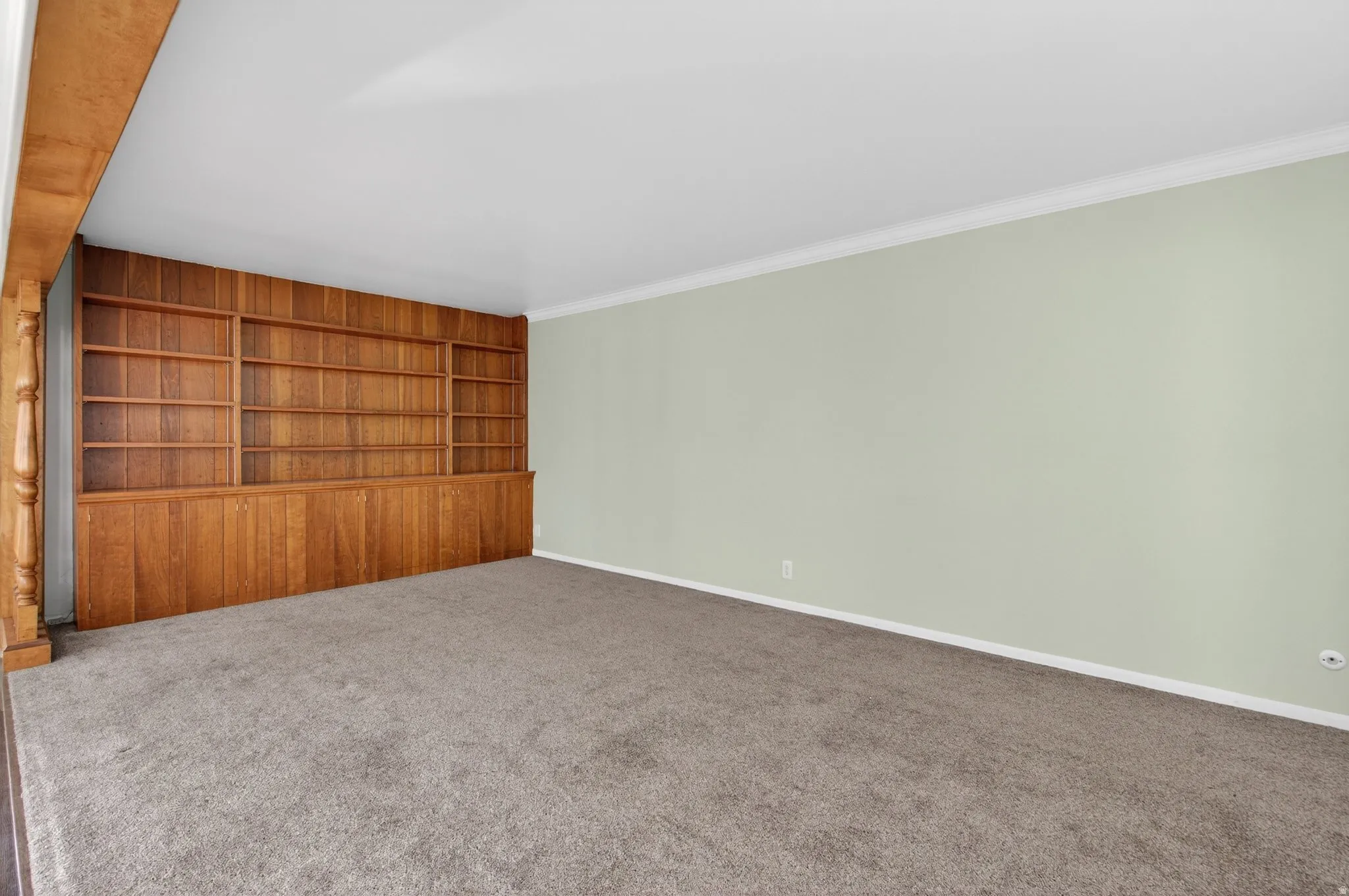 Carpeted room with built in shelves and baseboards