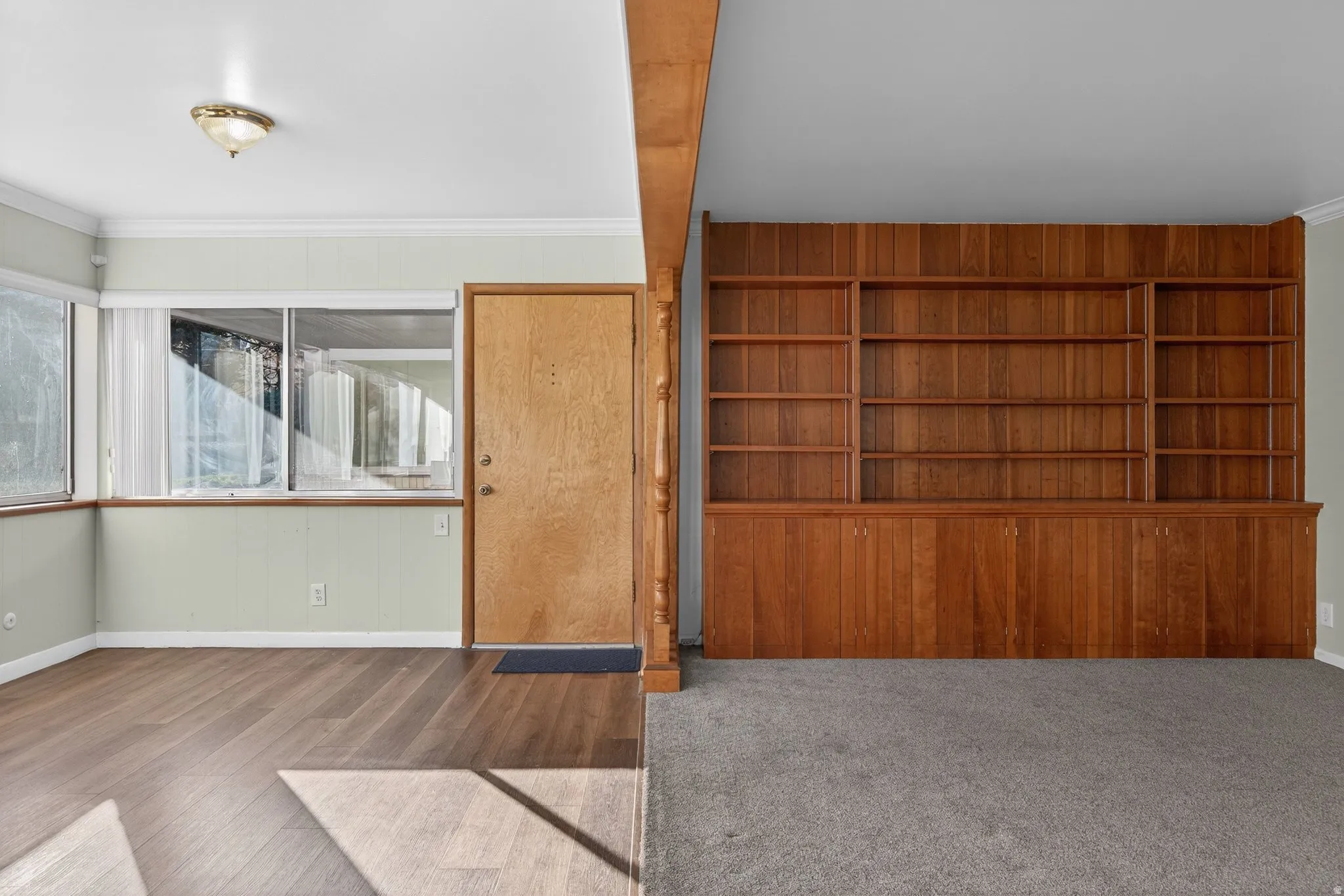 Unfurnished living room with crown molding and wood finished floors