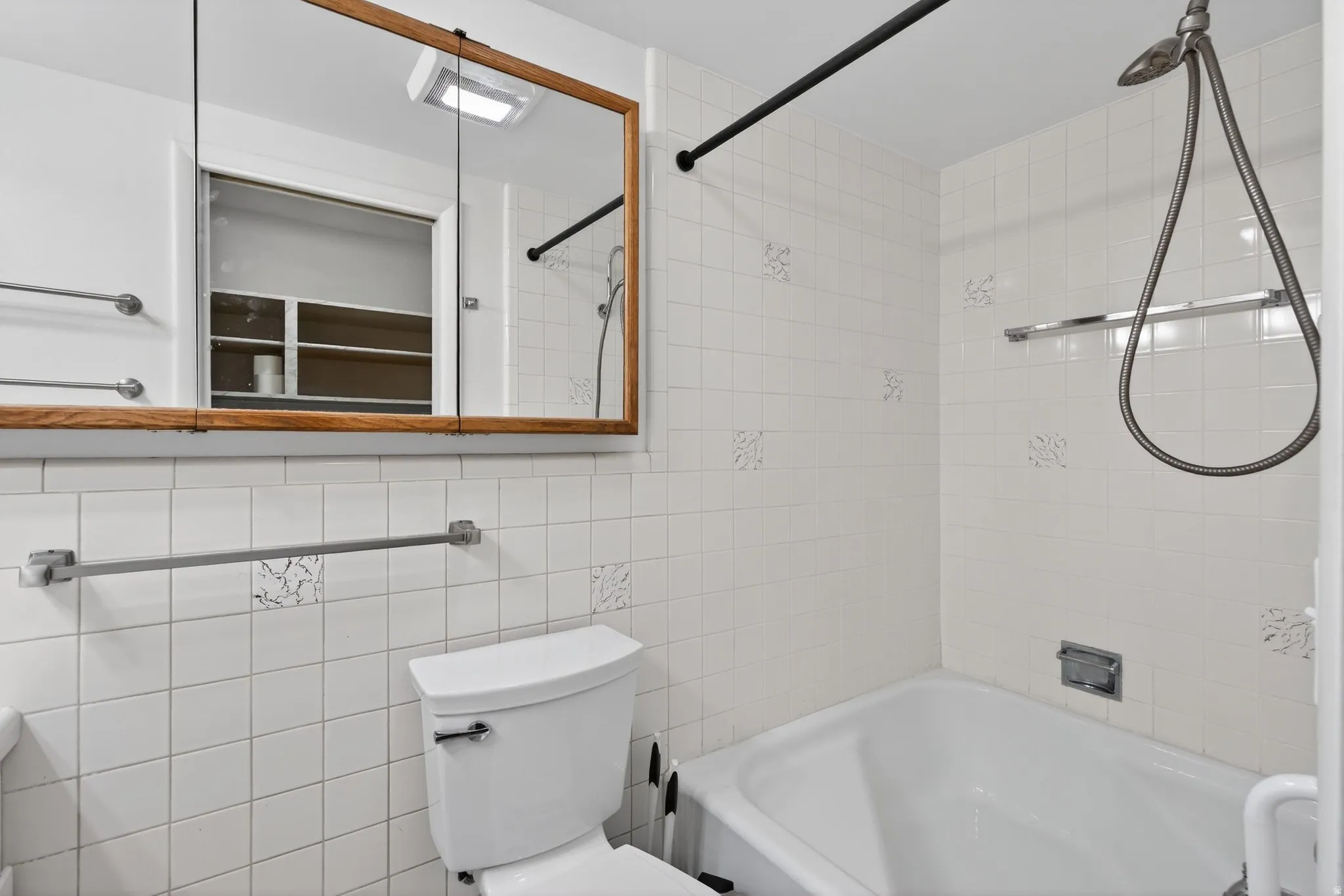 Bathroom featuring tub / shower combination and tile walls