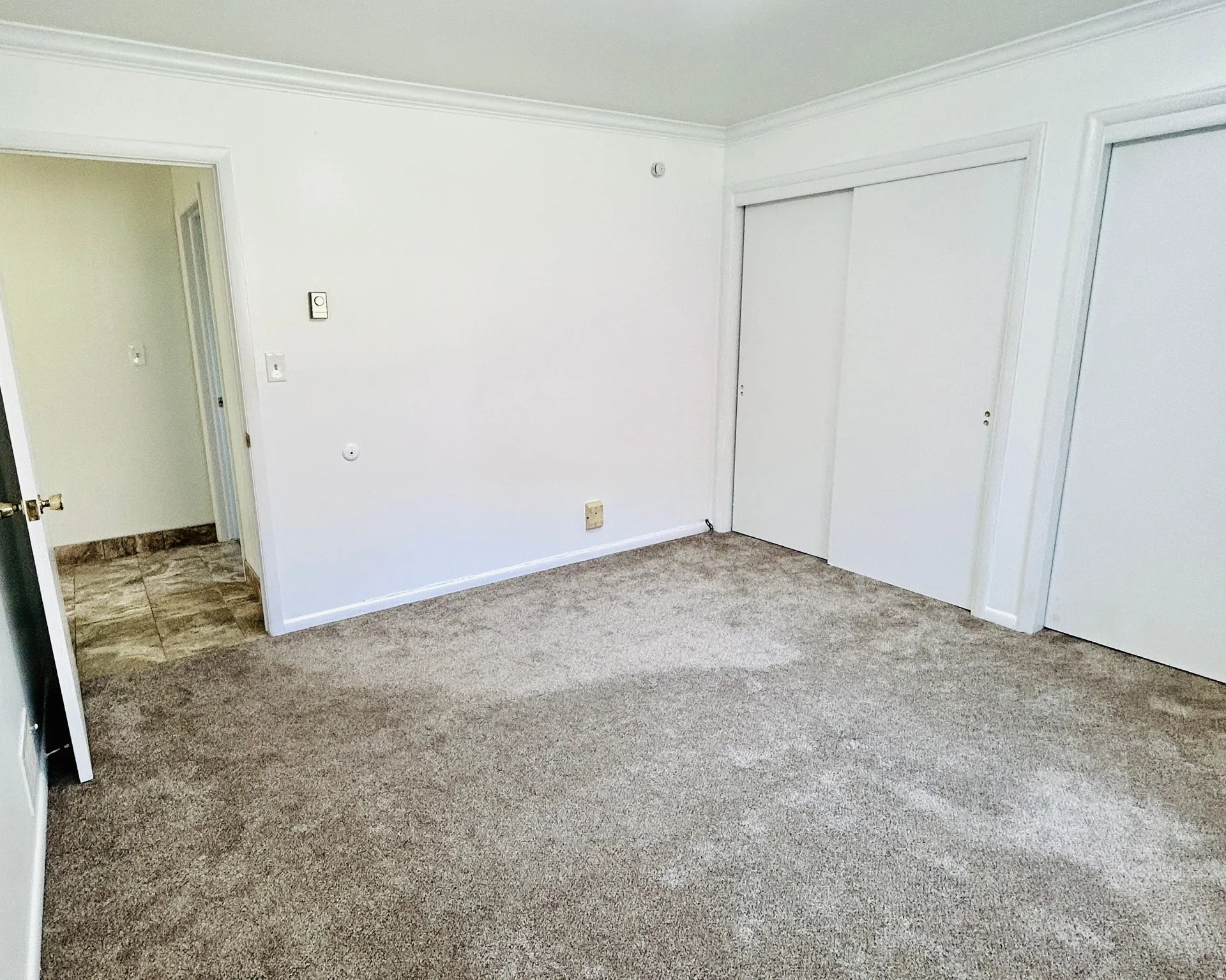 Primary bedroom. Neutral-toned carpet flooring complementing white walls and crown molding